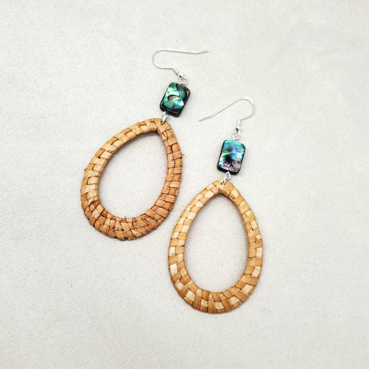 Pair of woven cedar earrings with abalone bead accents on a light gray background