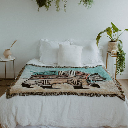 Hopi bear design throw blanket displayed across end of a bed.