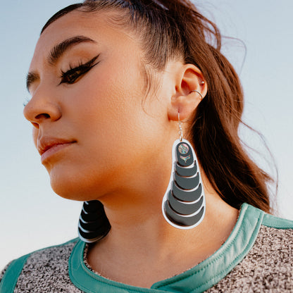 A model in profile wears the "Coastal Strata" earring in black acrylic by Copper Canoe Woman.