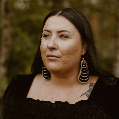 Model wearing the black acrylic version of the "Coastal Strata" earring by Copper Canoe Woman.