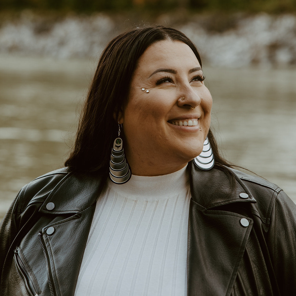 A smiling model wears the "Coast Strata" earring in silver, by Copper Canoe Woman.