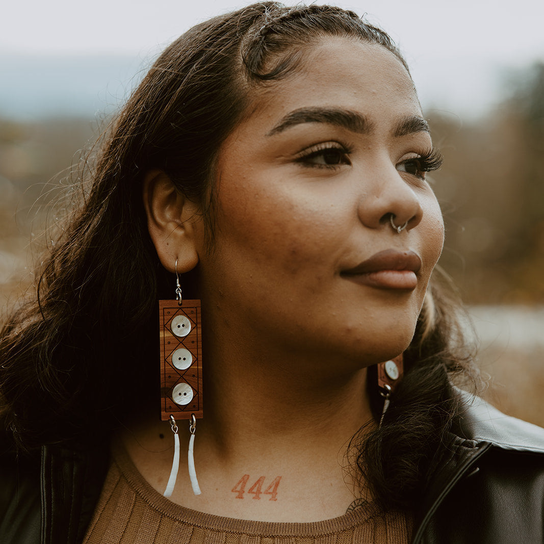 A model wearing a pair of "Echoes of Celebration" earrings from Copper Canoe Woman.