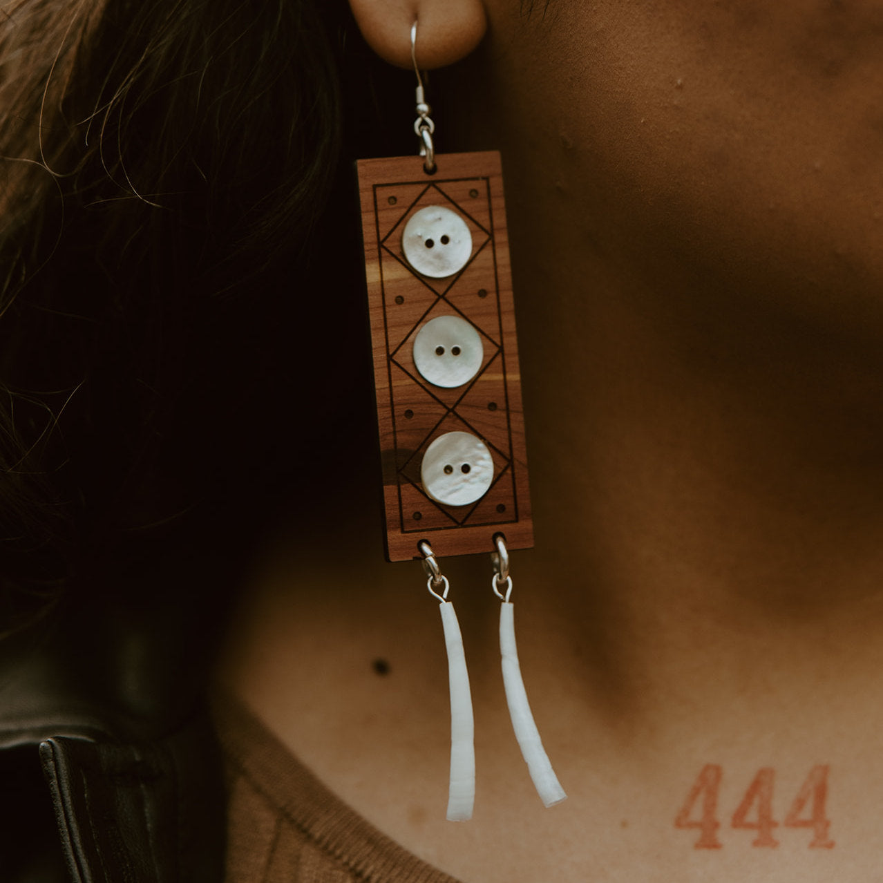 Closeup of a model wearing "Echoes of Celebration" earrings in cedar wood from Copper Canoe Woman.