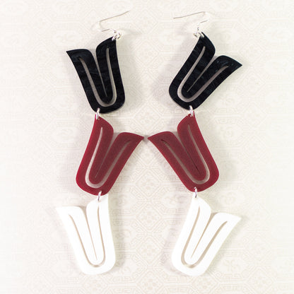 A pair of "Formline Cascade" earrings from Copper Canoe Woman laying on white fabric in the mixed colorway option.