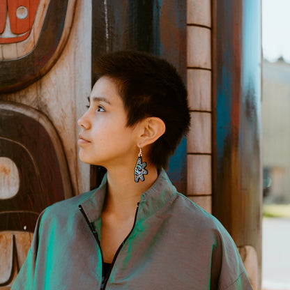 A youth model stares into the distance wearing the "Hupal" sun and moon earrings from Copper Canoe Woman.