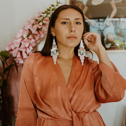 Copper Canoe Woman "Mesa" earrings in rose gold and blush color acrylic worn by a model.