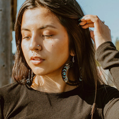 Woman wearing a Nala Hoop earring from Copper Canoe Woman in black acrylic.