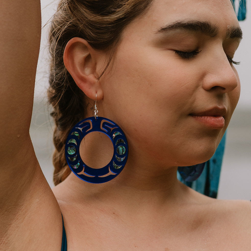 Close-up of a person wearing a cobalt mirror acrylic Nala Hoop earring with abalone inlay from Copper Canoe Woman.