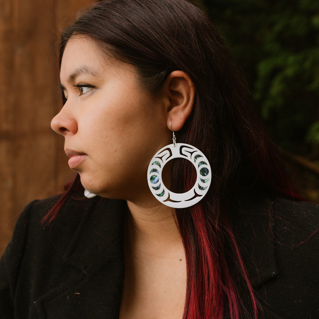 Profile of a model in close-up wearing a white acrylic Nala Hoop earring from Copper Canoe Woman.