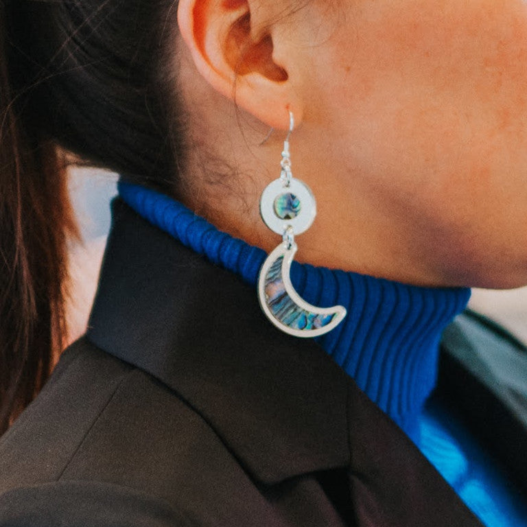 Closeup of a model in "Nuci" crescent moon earrings from Copper Canoe Woman in silver mirror acrylic.