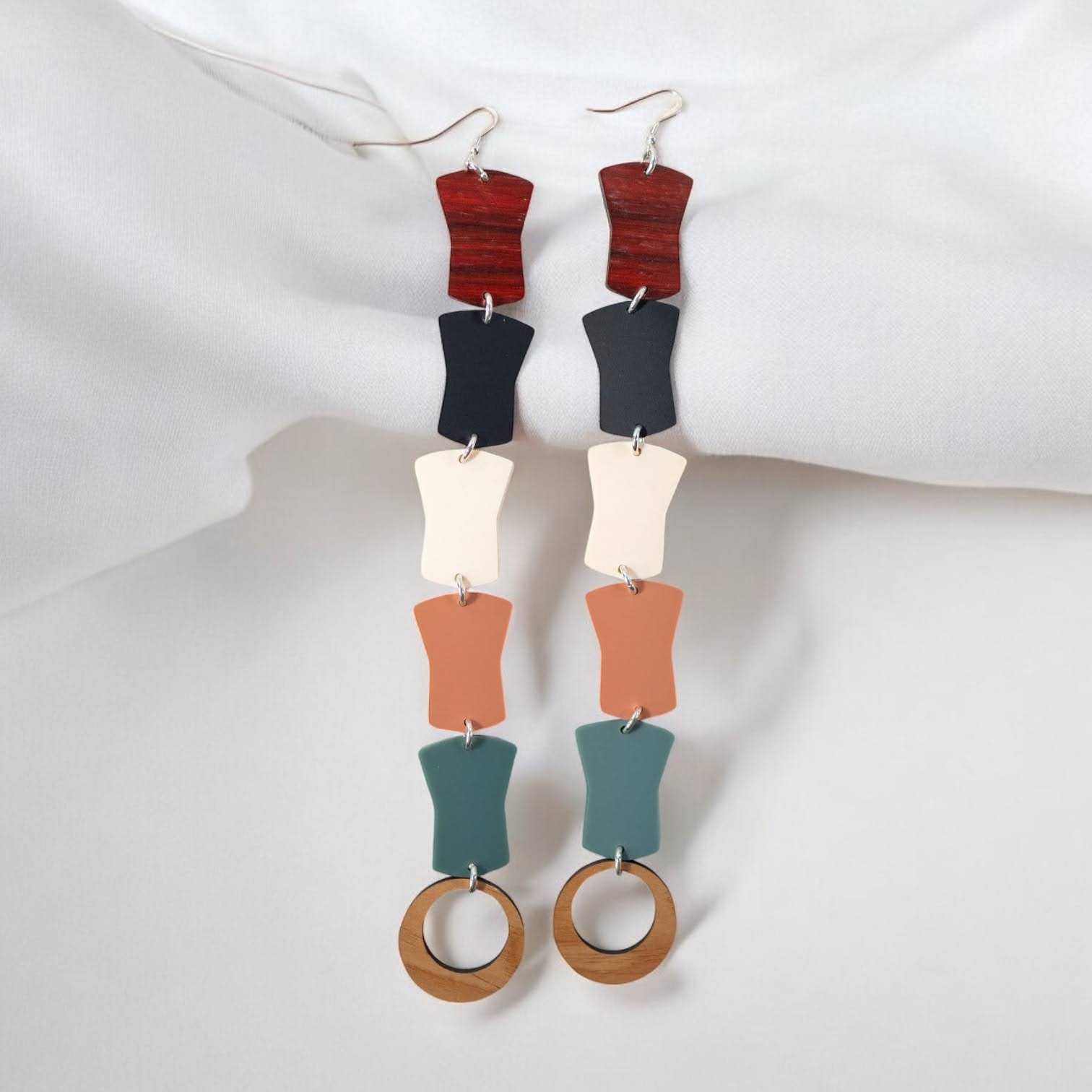A pair of "Opulence Flow" earrings from Copper Canoe Woman laying on white fabric.