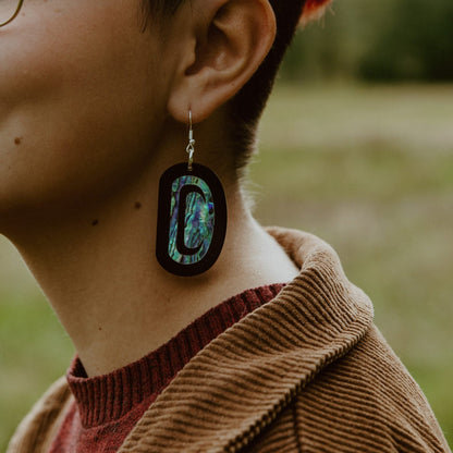Closeup of black acrylic "Abalone Ovoid" earrings from Copper Canoe Woman.