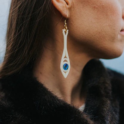 Ivory acrylic "Paddle Song" earring from Copper Canoe Woman worn by a model.