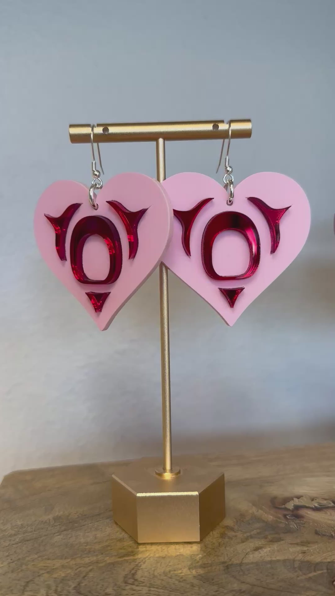 video panning from copper canoe woman all my heart earrings in pink acrylic to a pair of copper canoe woman all my heart earrings in cedar. 
