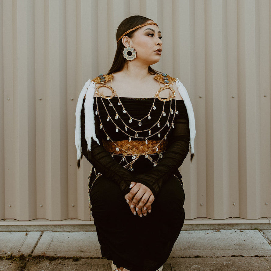 Woman in traditional outfit sitting against a corrugated metal wall