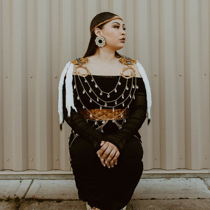 Woman in traditional outfit sitting against a corrugated metal wall