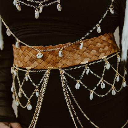 Person wearing a woven belt with gold chain and pearl embellishments.