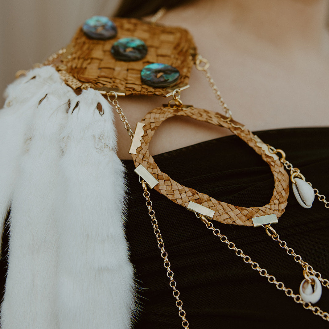 Close-up of a person wearing a decorative arm piece with furs and beads.