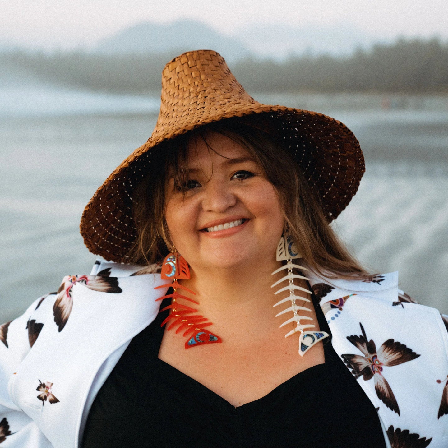 Model wearing one red and one ivory large salmon ghost earrings in acrylic from Copper Canoe Woman.