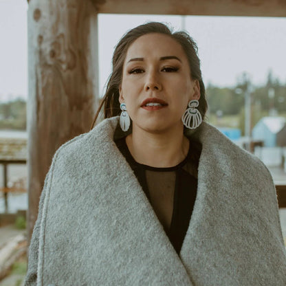 A model stares into the camera in pearl acrylic "Shell Woman" earrings from Copper Canoe Woman.