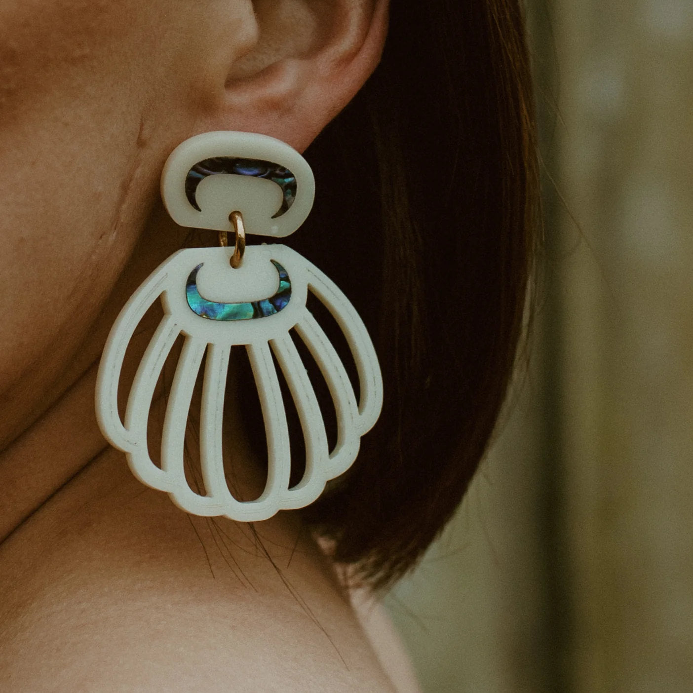 Close up of a model wearing ivory acrylic "Shell Woman" earrings from Copper Canoe Woman.