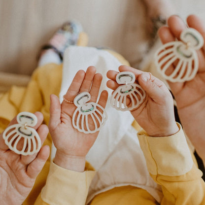 Hands hold pairs of Shell Woman earrings from Copper Canoe Woman in open palms.