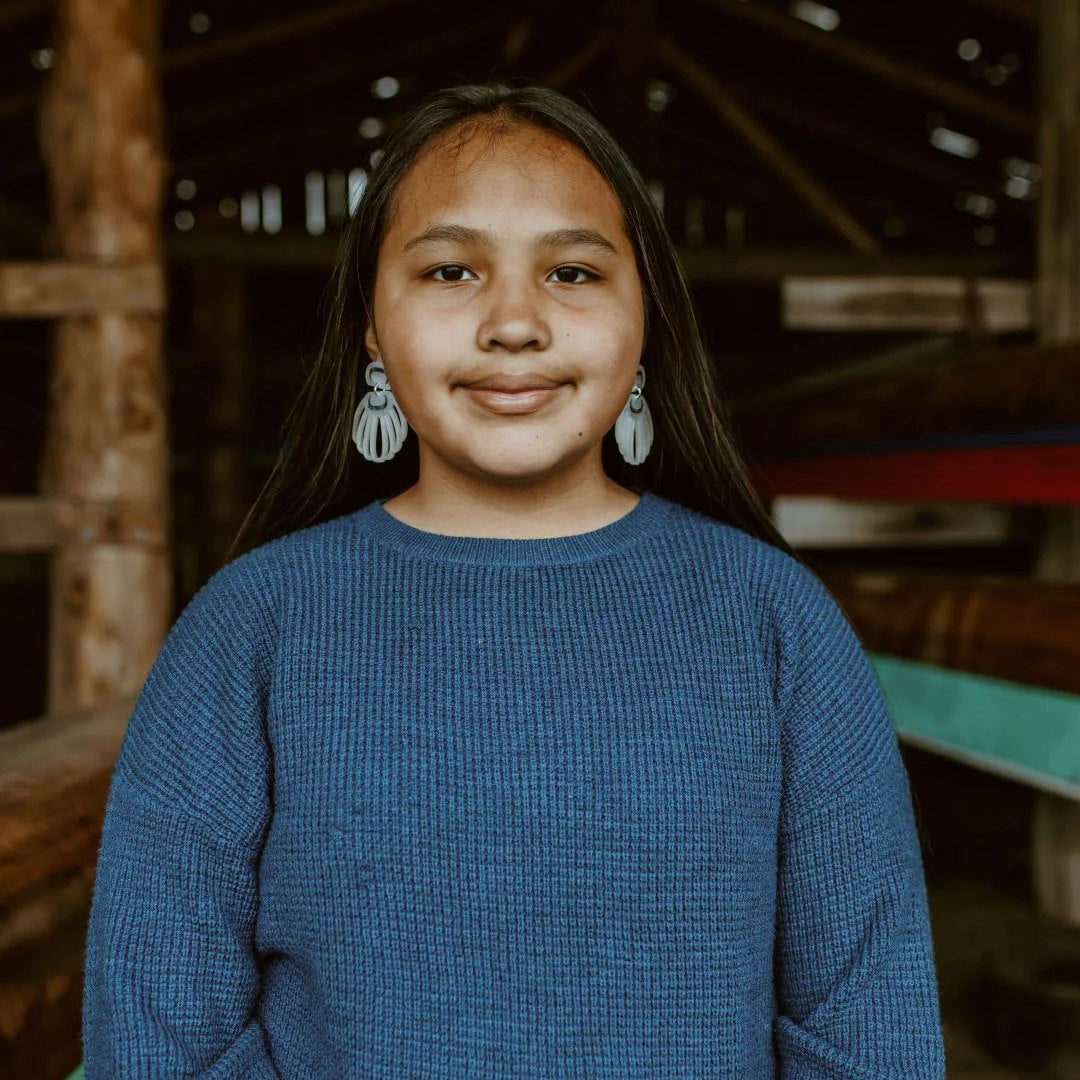 A youth model wears pearl acrylic "Shell Woman" earrings from Copper Canoe Woman.