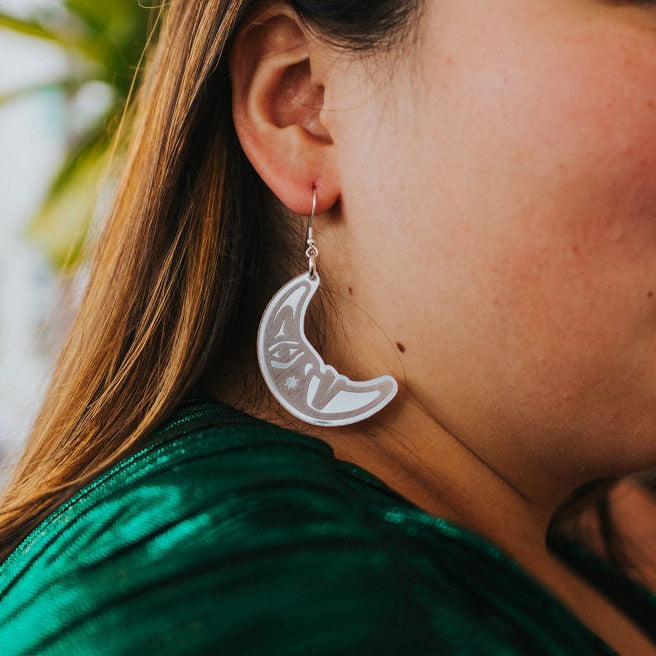 close up of woman wearing silver acrylic crescent moon engraved with formline art from copper canoe woman
