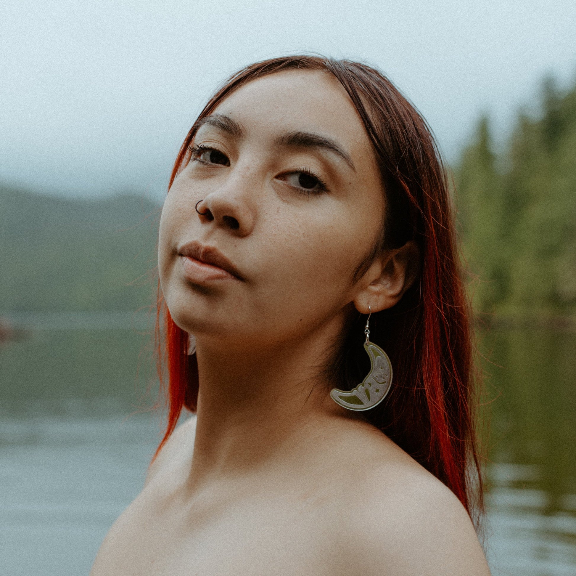 woman wearing silver acrylic crescent moon engraved with formline art from copper canoe woman