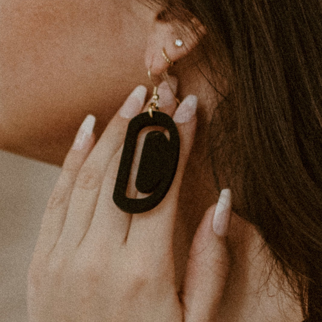 Woman wearing teal small ovoid earrings.