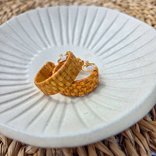 Hand-woven cedar clip-on hoop earrings from Copper Canoe Woman on a white plate with a braided surface background.