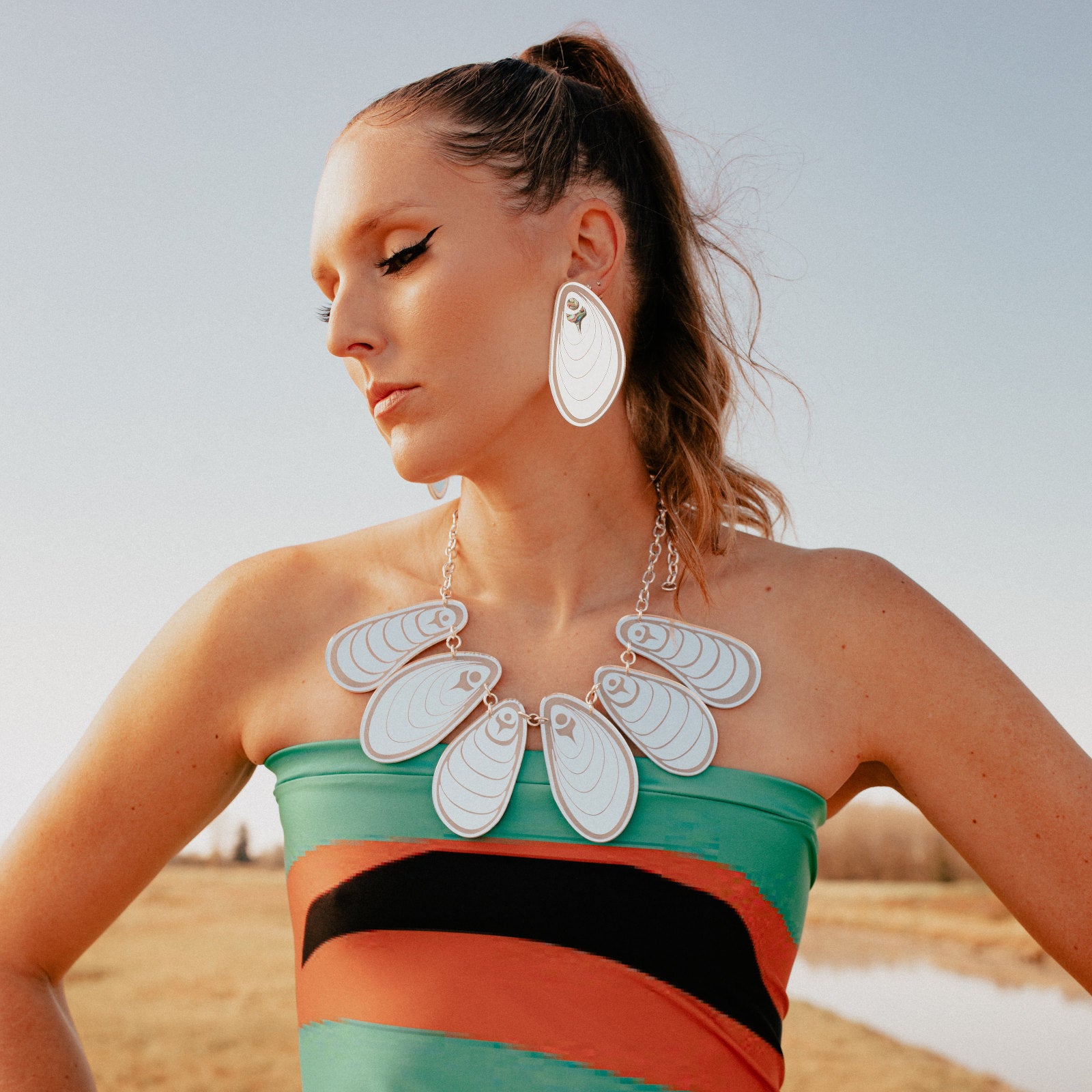 A model wearing the mussel-inspired "Tidal Reflections" necklace from Copper Canoe Woman and matching earrings.