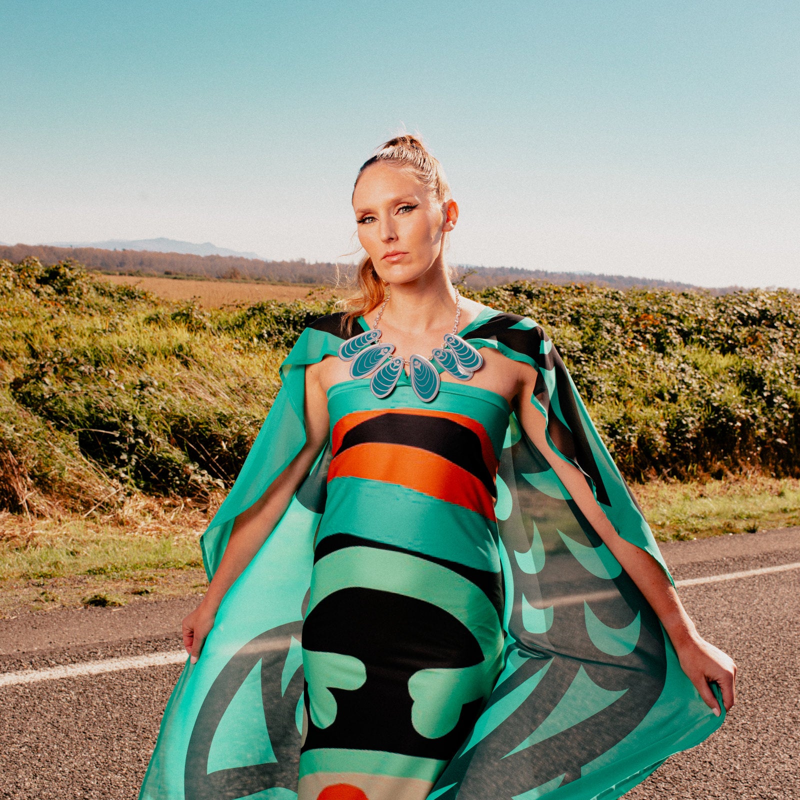 A model stands on a road wearing the "Tidal Reflections" necklace by Copper Canoe Woman.