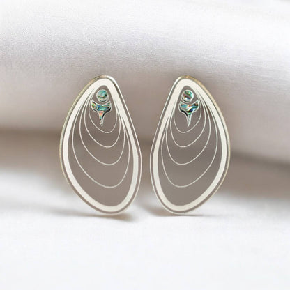 A pair of silver mirror "Tidal Ripples" earrings from Copper Canoe Woman stand against a fold of white fabric.
