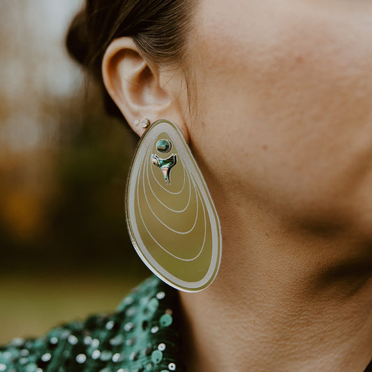 Closeup of model wearing mussel-inspired "Tidal Ripples" earring in silver mirror acrylic from Copper Canoe Woman.
